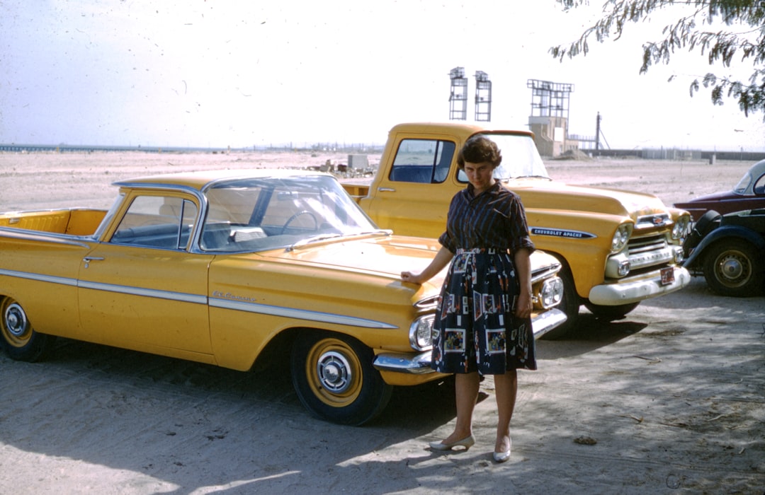 woman in black and white floral dress leaning on yellow car