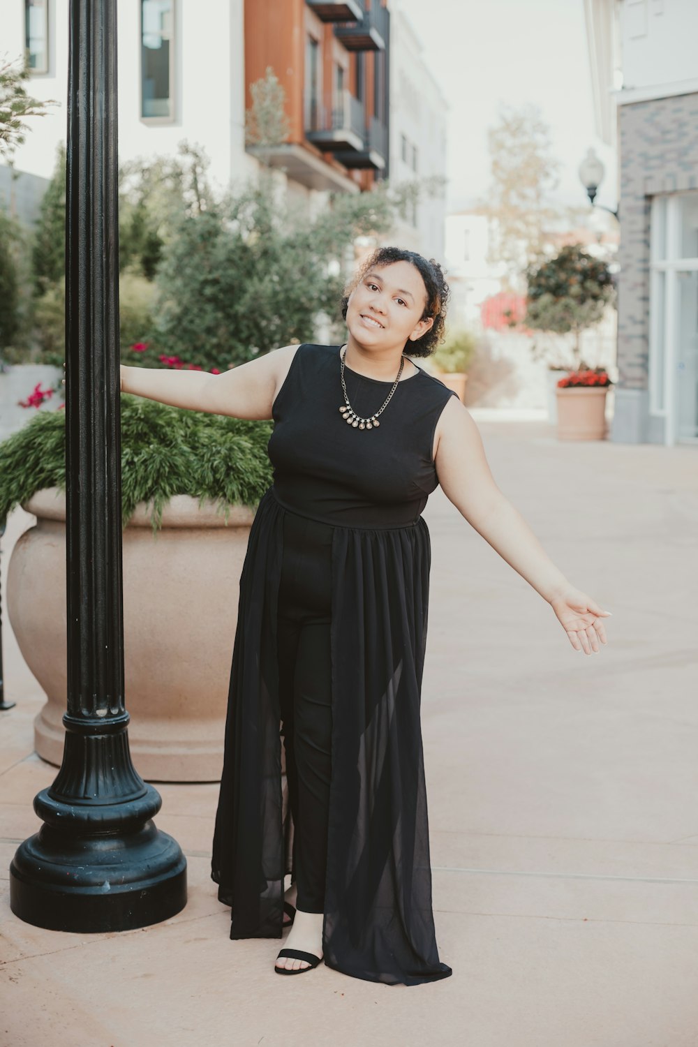 woman in black sleeveless dress standing near black post