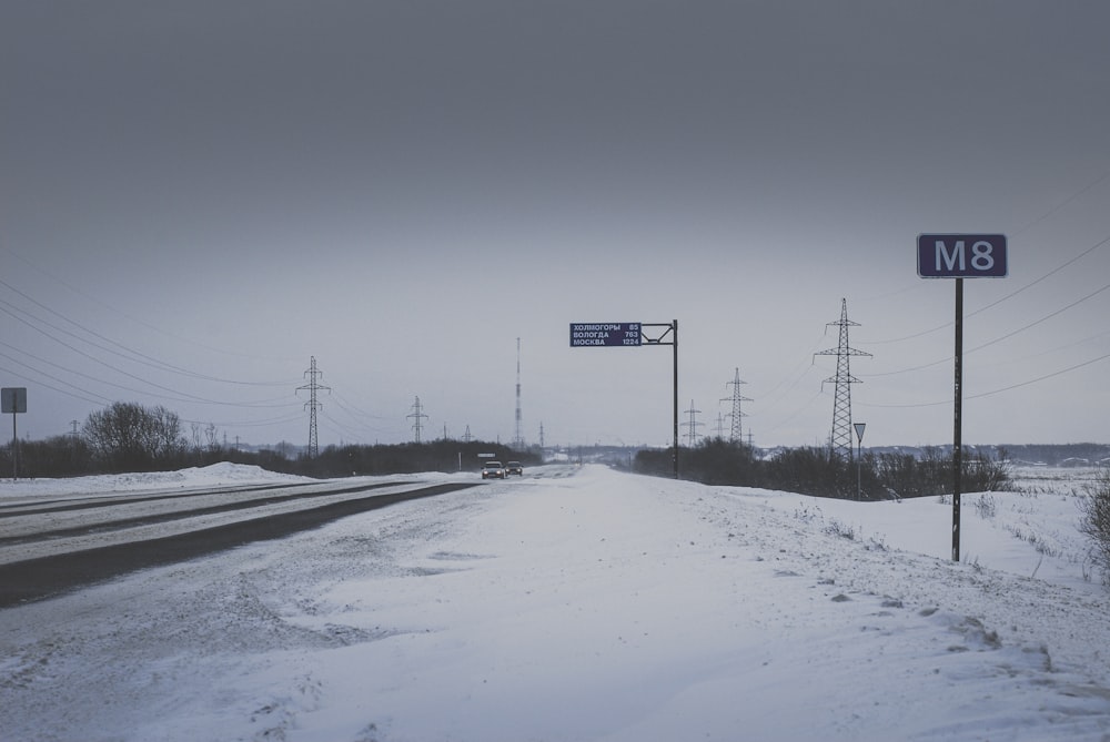 black and white road sign on snow covered ground