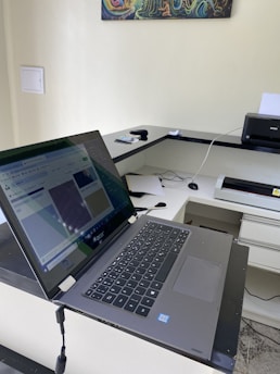 A sleek laptop, a modern printer, and various computer accessories arranged neatly on a desk.