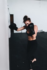 woman in black sports bra and black leggings wearing black boxing gloves