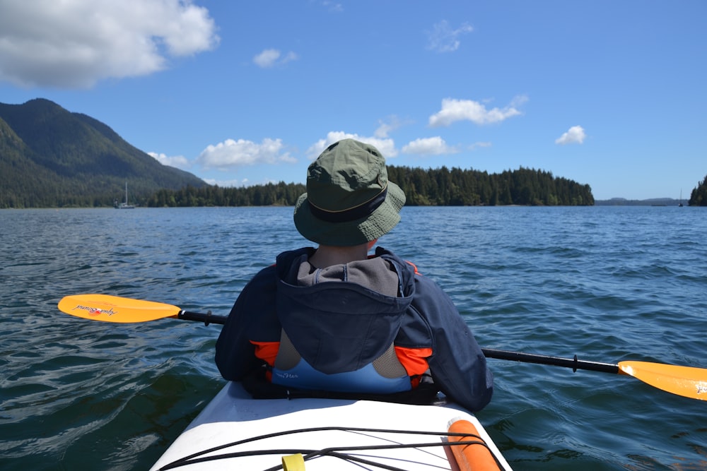 man in black and red jacket wearing gray cap riding on white and orange kayak on on on on on