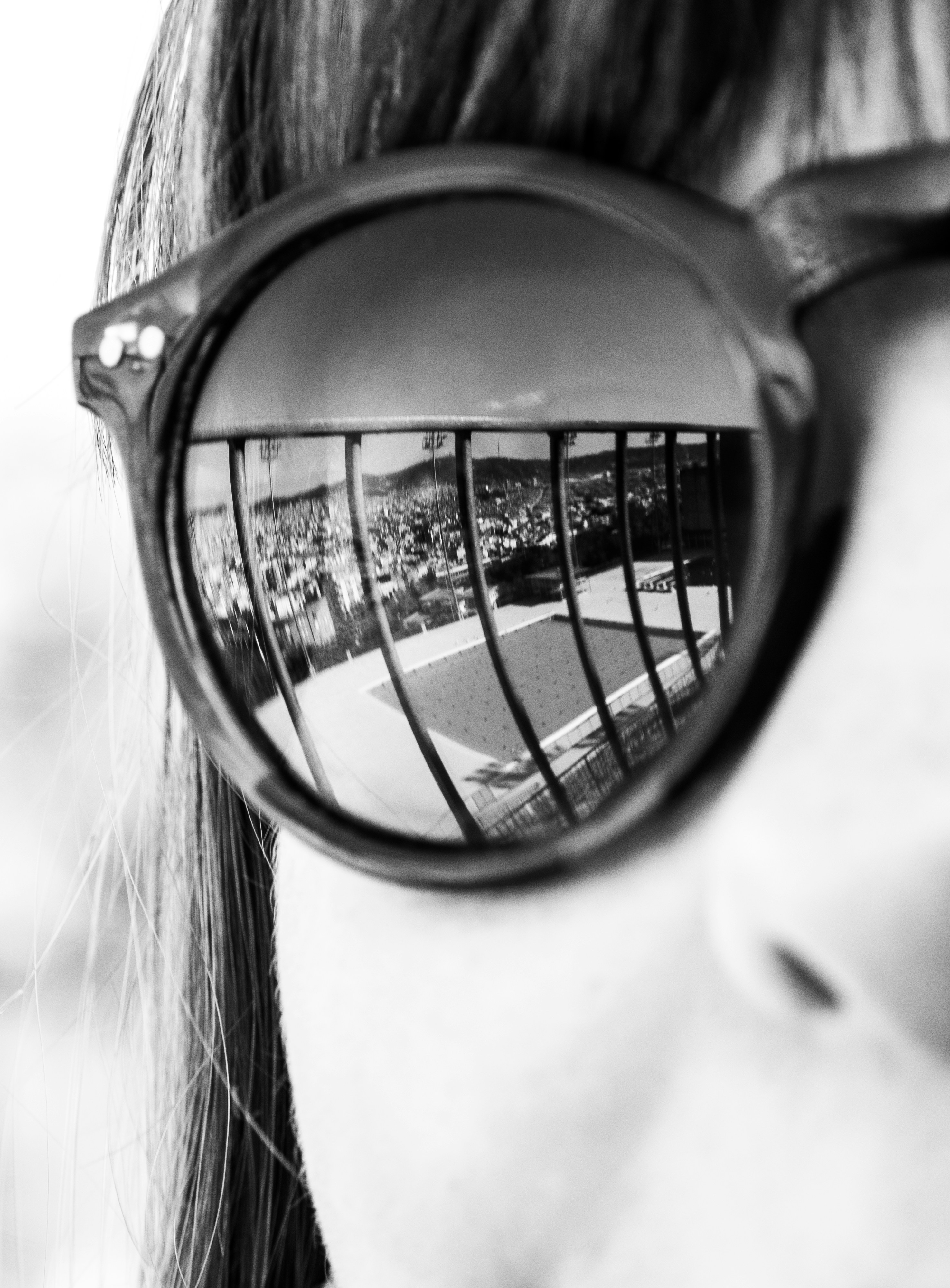 The swimming pool, used for the 1992 Barcelona Olympics, reflects in a girl's sunglasses.