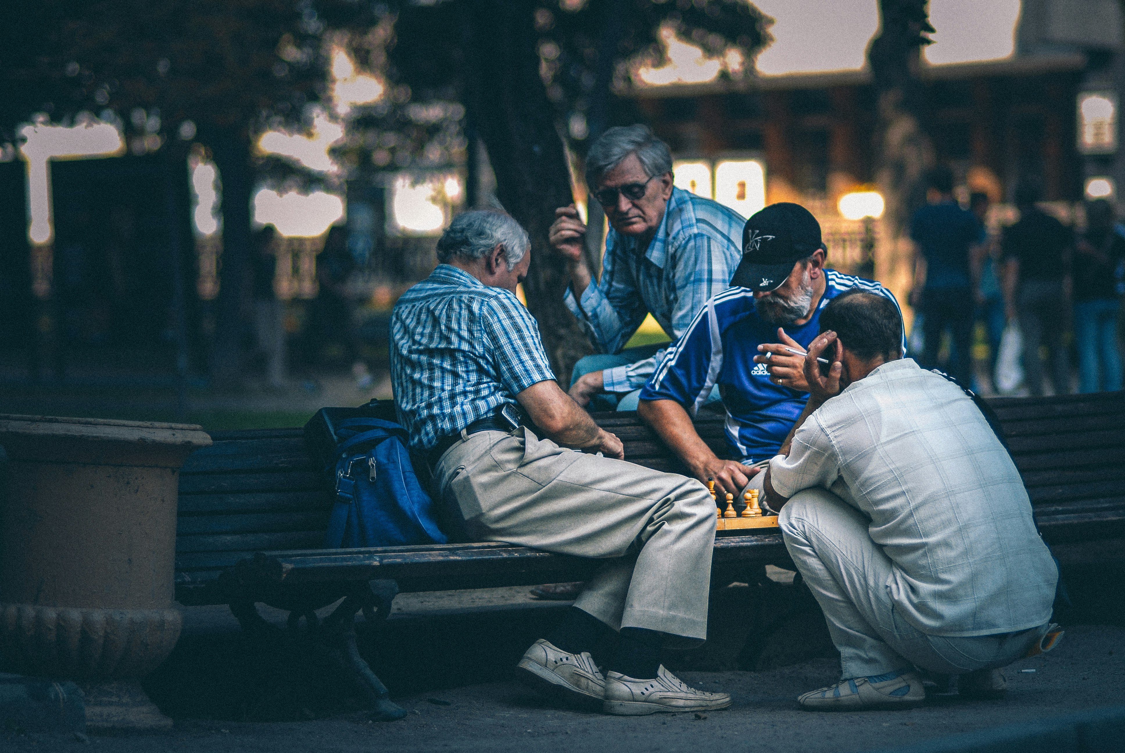 Men play chess on the bench in the park.