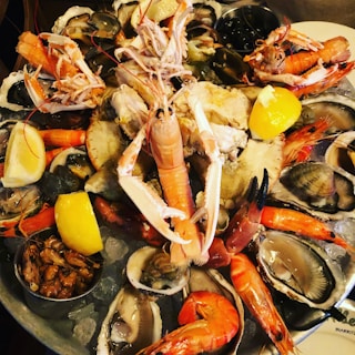 A bountiful seafood platter with a variety of shellfish, including prawns, clams, oysters, and crab claws, garnished with lemon wedges and served over a bed of ice.