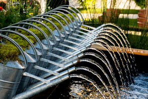 A set of watering cans in different sizes lined up on a wooden garden bench.