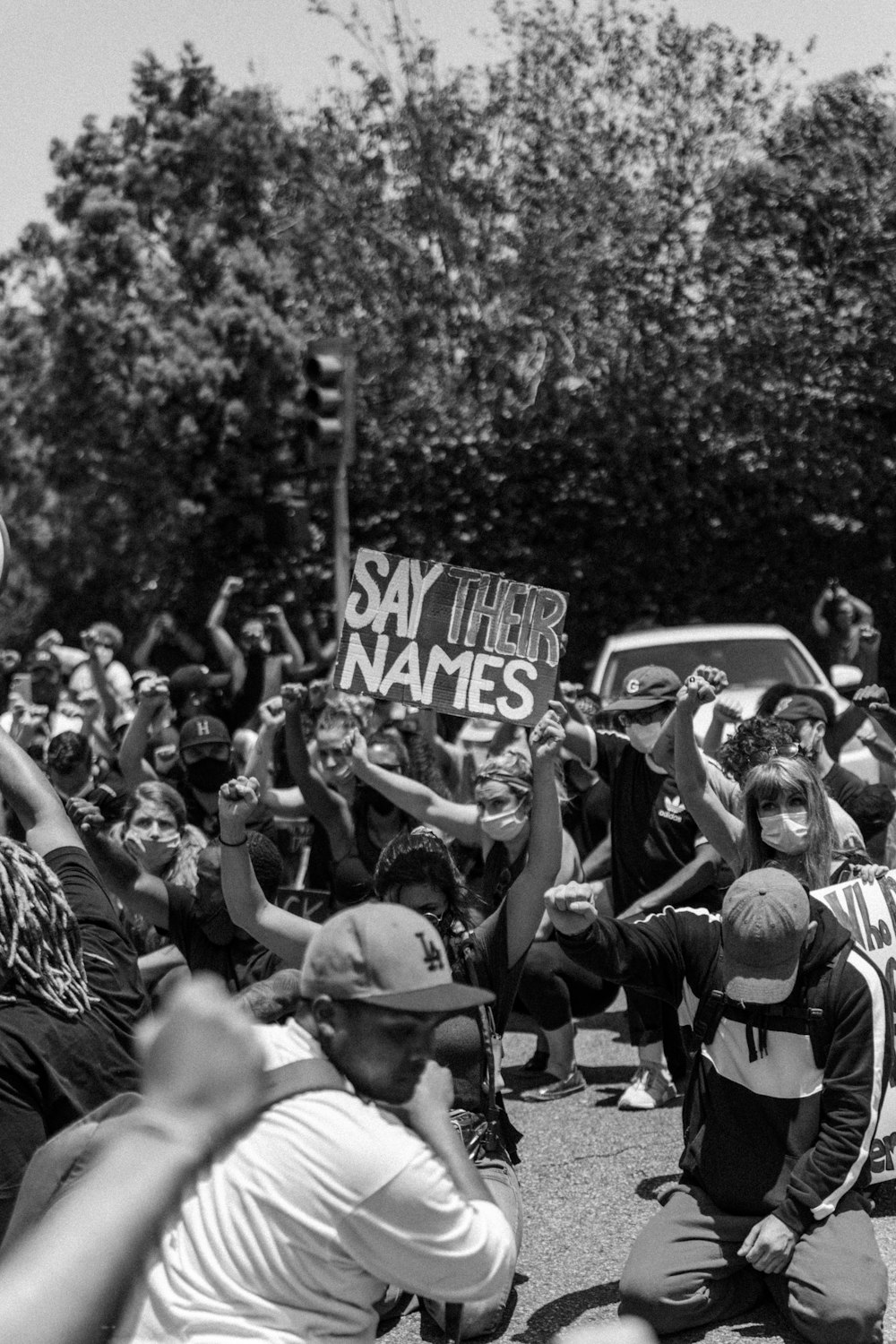 foto em tons de cinza de pessoas em pé perto de árvores