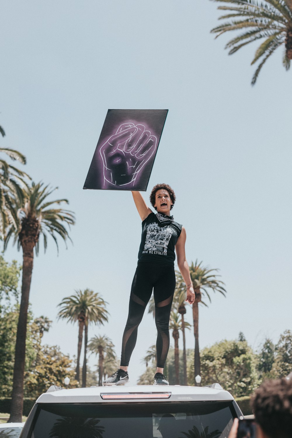 woman in black and white shirt standing near palm tree during daytime