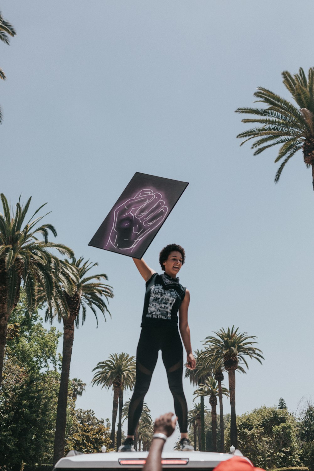 woman in black and white shirt and black pants standing under purple umbrella