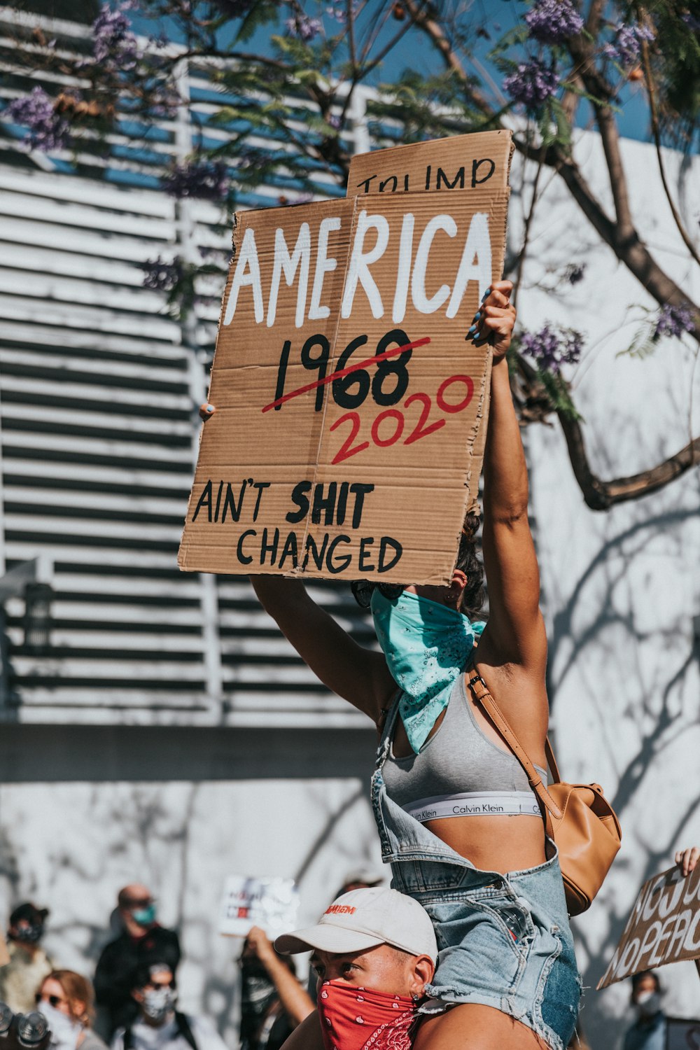 woman in blue and white bikini bottom holding brown wooden signage