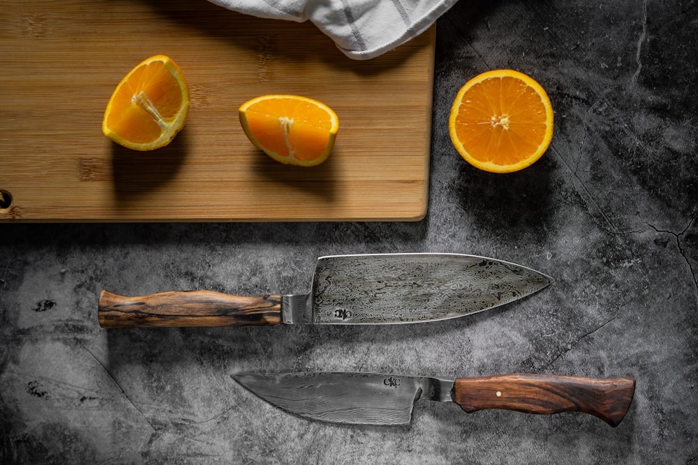 in Scheiben geschnittene Orangenfrüchte neben Messer und Messer auf Schneidebrett