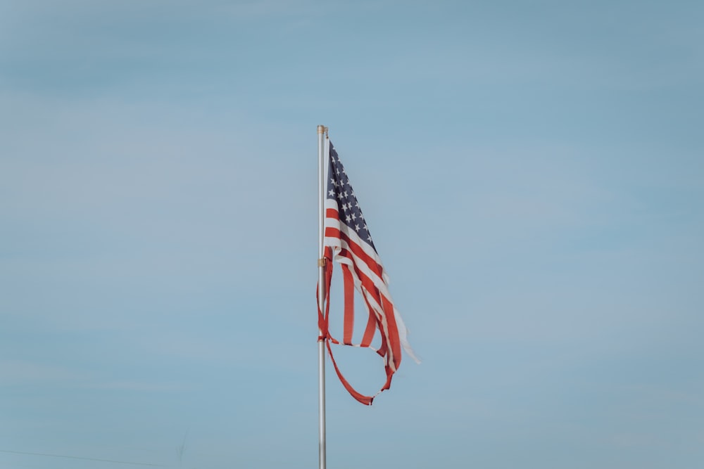 Una bandera en el mástil bajo el cielo azul durante el día