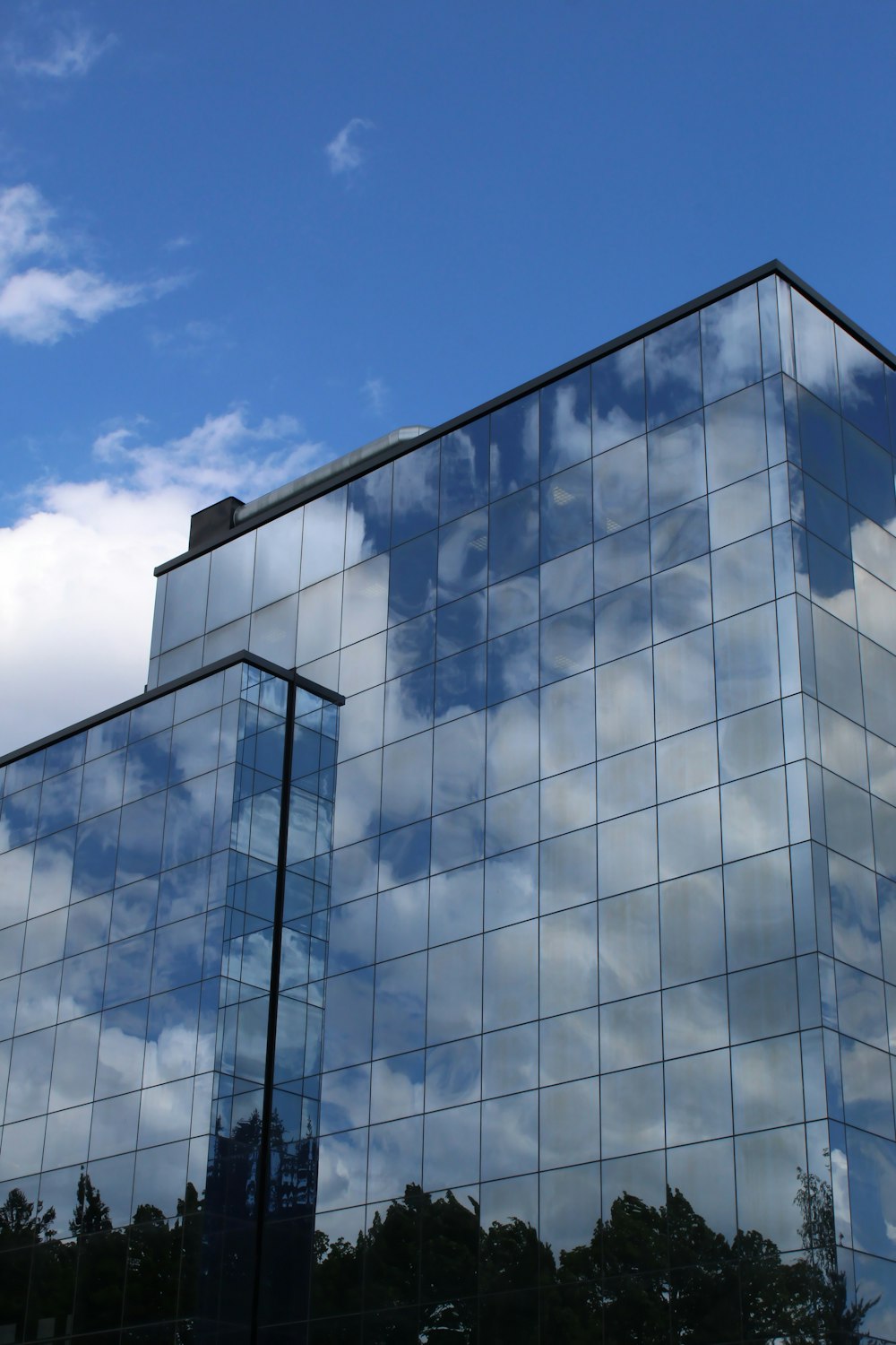 edifício de vidro azul e branco sob o céu azul durante o dia