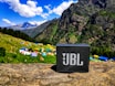 A vibrant bluetooth speaker playing music outdoors with mountains visible in the background, capturing nepalgizmo's adventurous spirit.