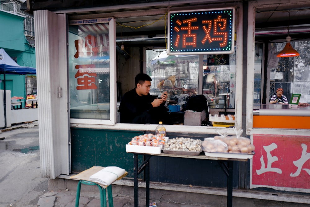 man in black t-shirt standing in front of food stall