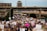 A large crowd of people gathers in a protest, holding signs with slogans related to social justice and equality. The scene takes place on a street with overpasses and buildings in the background. The signs have messages like 'Black Lives Matter' and 'Justice'.