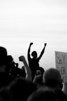 grayscale photo of people raising their hands