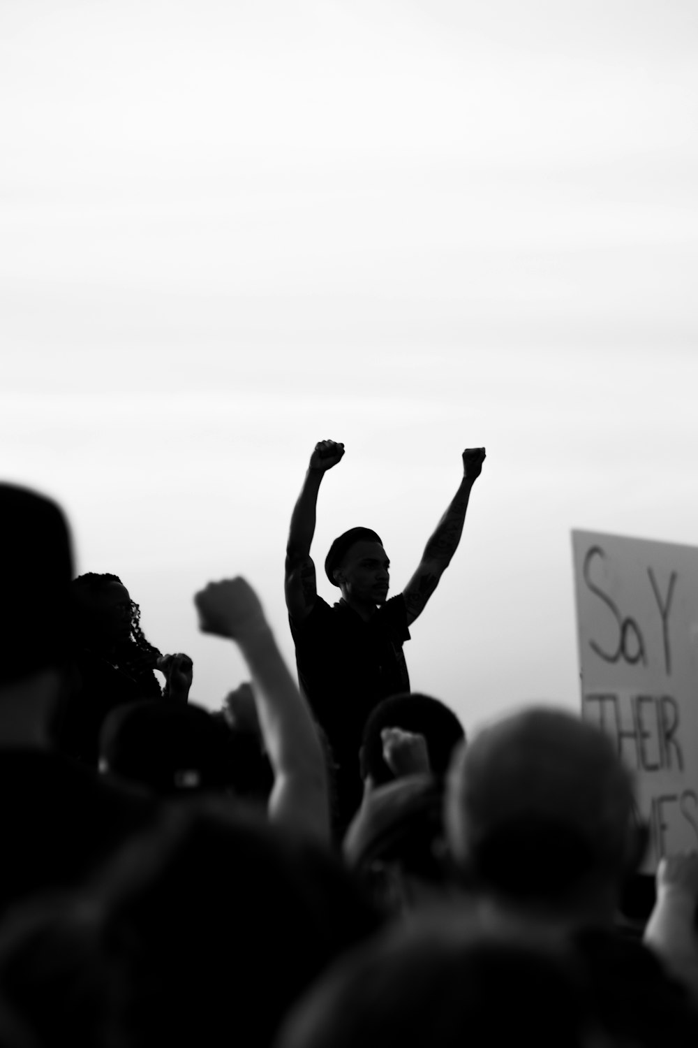 foto em tons de cinza de pessoas levantando as mãos