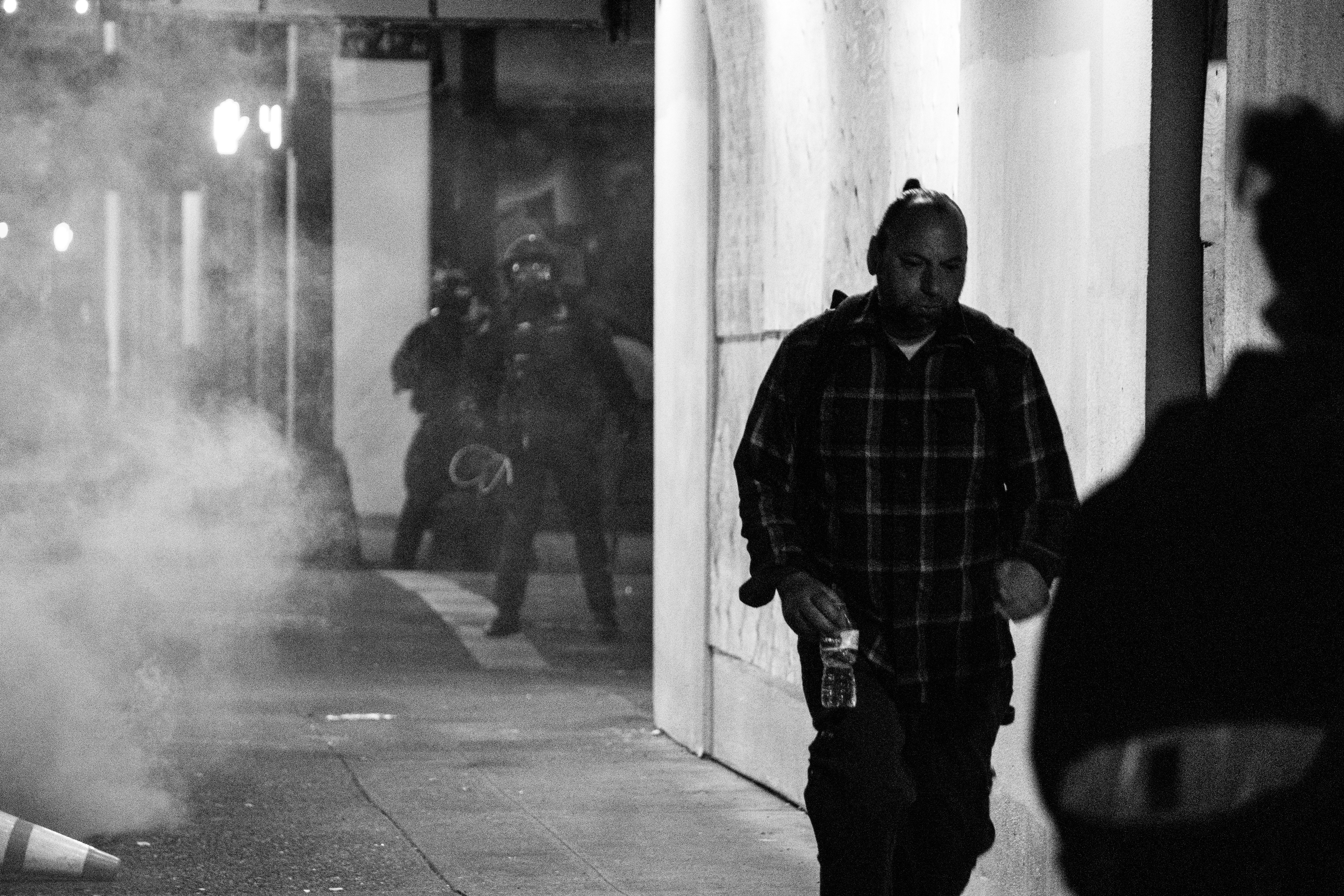 man in black and white plaid dress shirt standing beside white wall