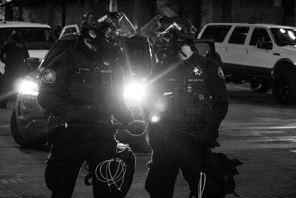 Foto en escala de grises de 2 hombres con casco negro y casco