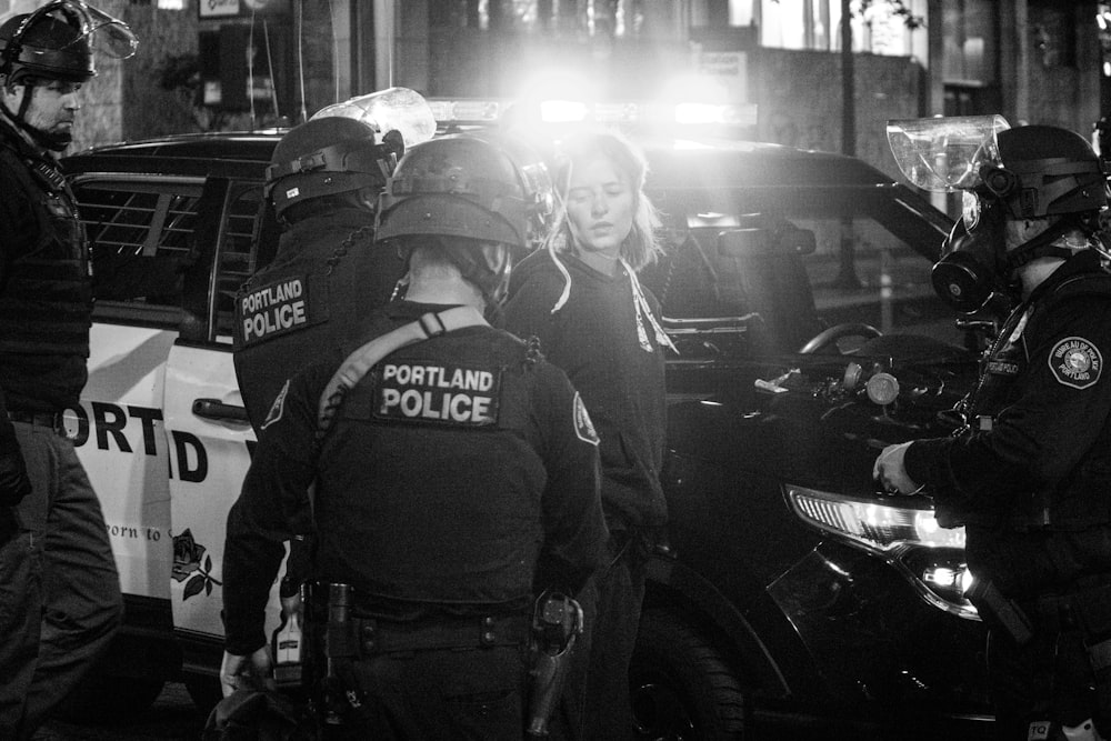 Photo en niveaux de gris d’un homme en costume de police debout à côté d’une moto