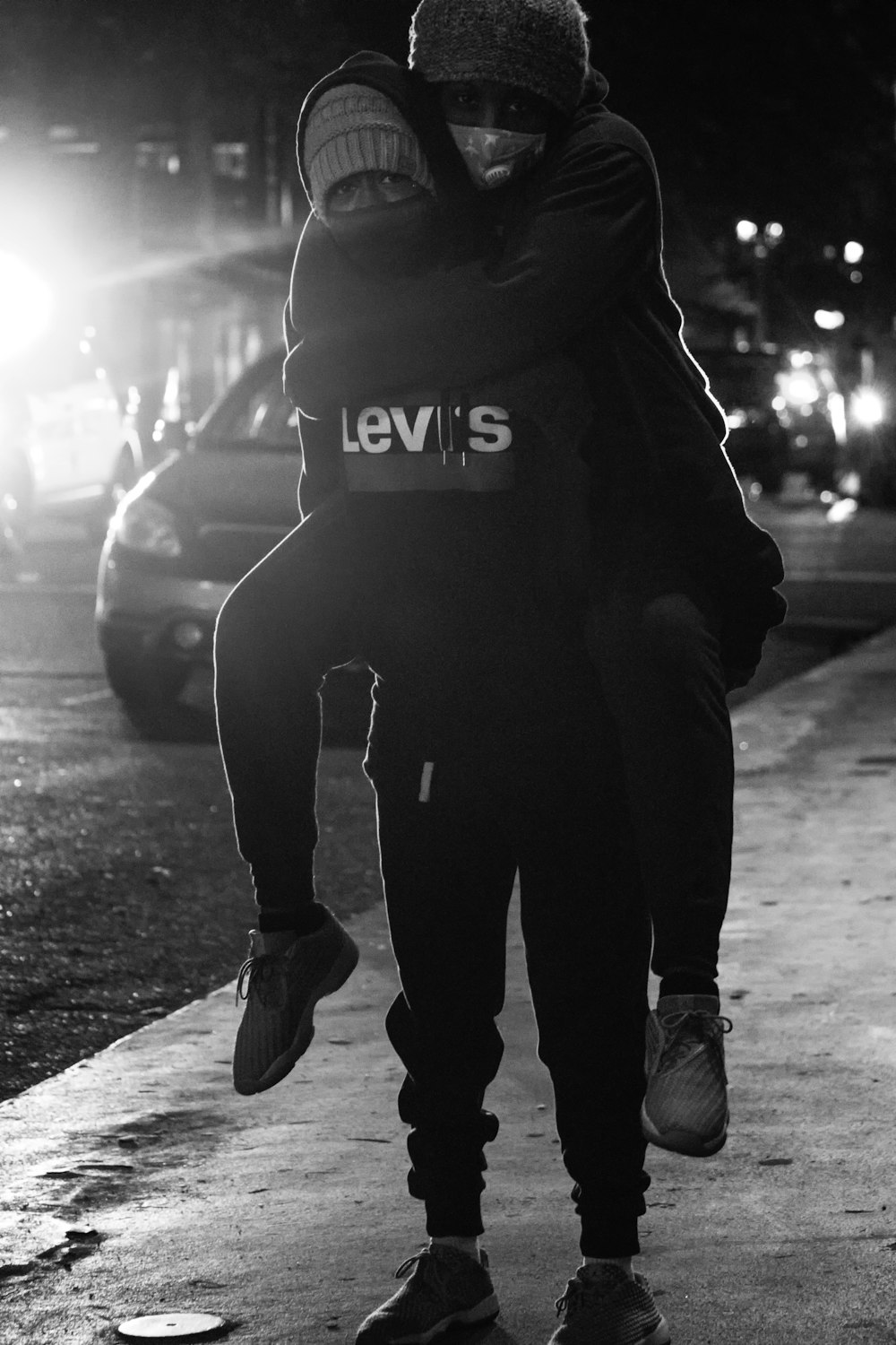 man in black hoodie and black pants walking on street during night time