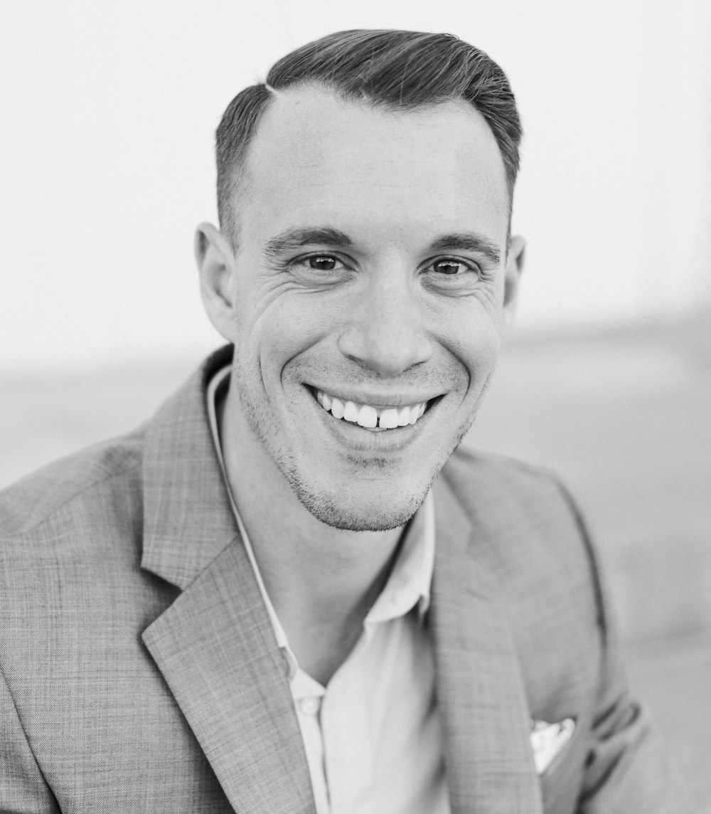 man in gray suit jacket smiling