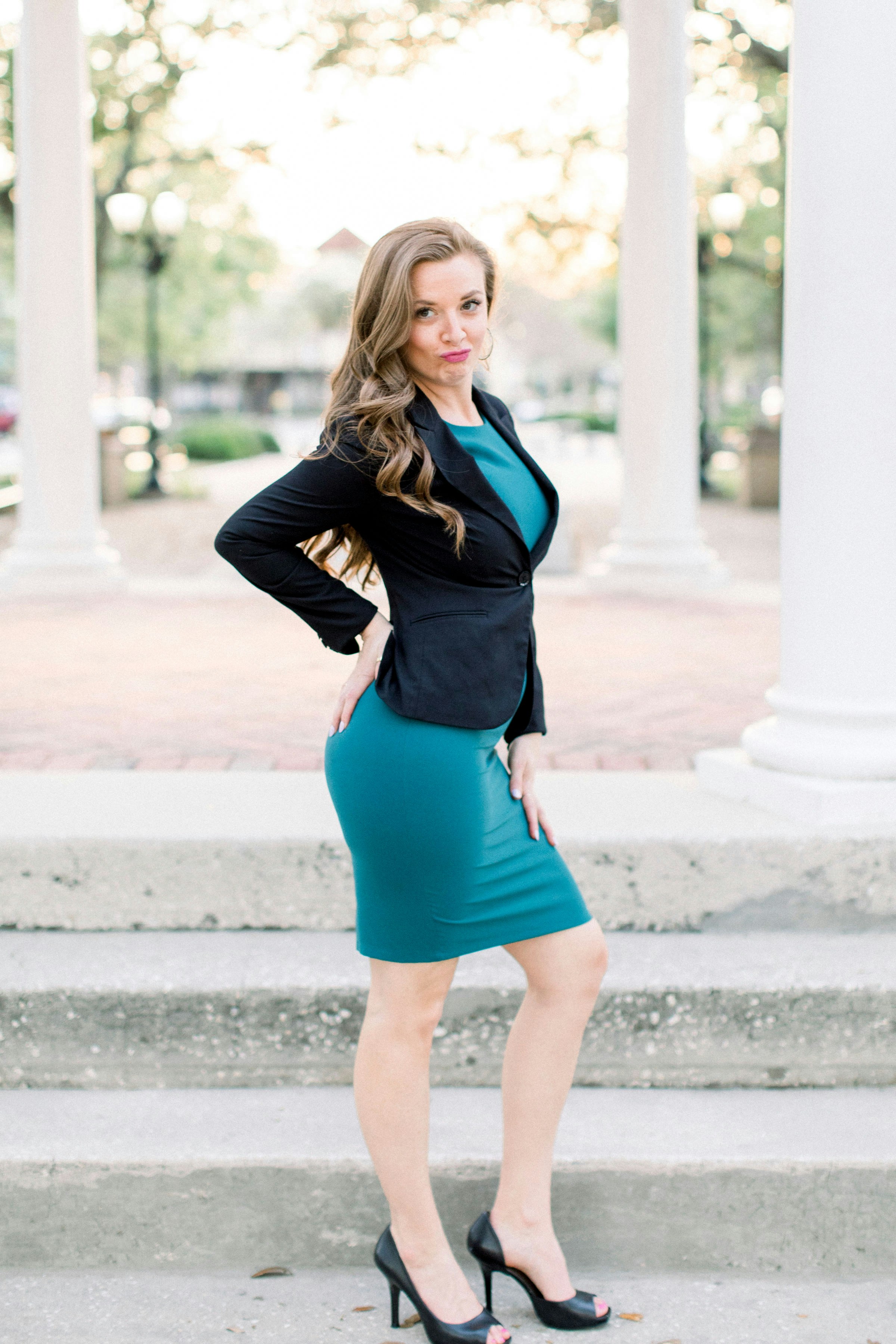 woman in black leather jacket and blue mini skirt standing on gray concrete floor during daytime