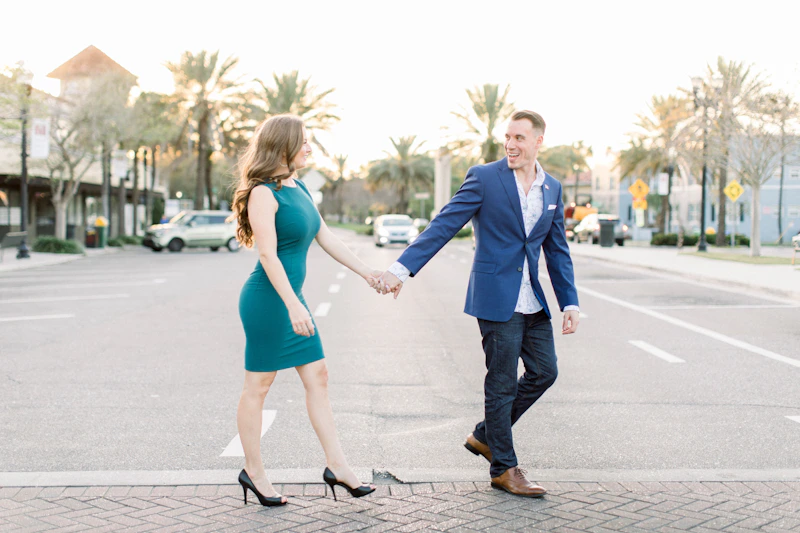 man in blue suit holding woman in blue dress walking on sidewalk during daytime