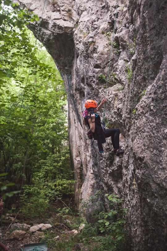 man in black shirt climbing on gray rocky mountain during daytime in Transylvania Romania