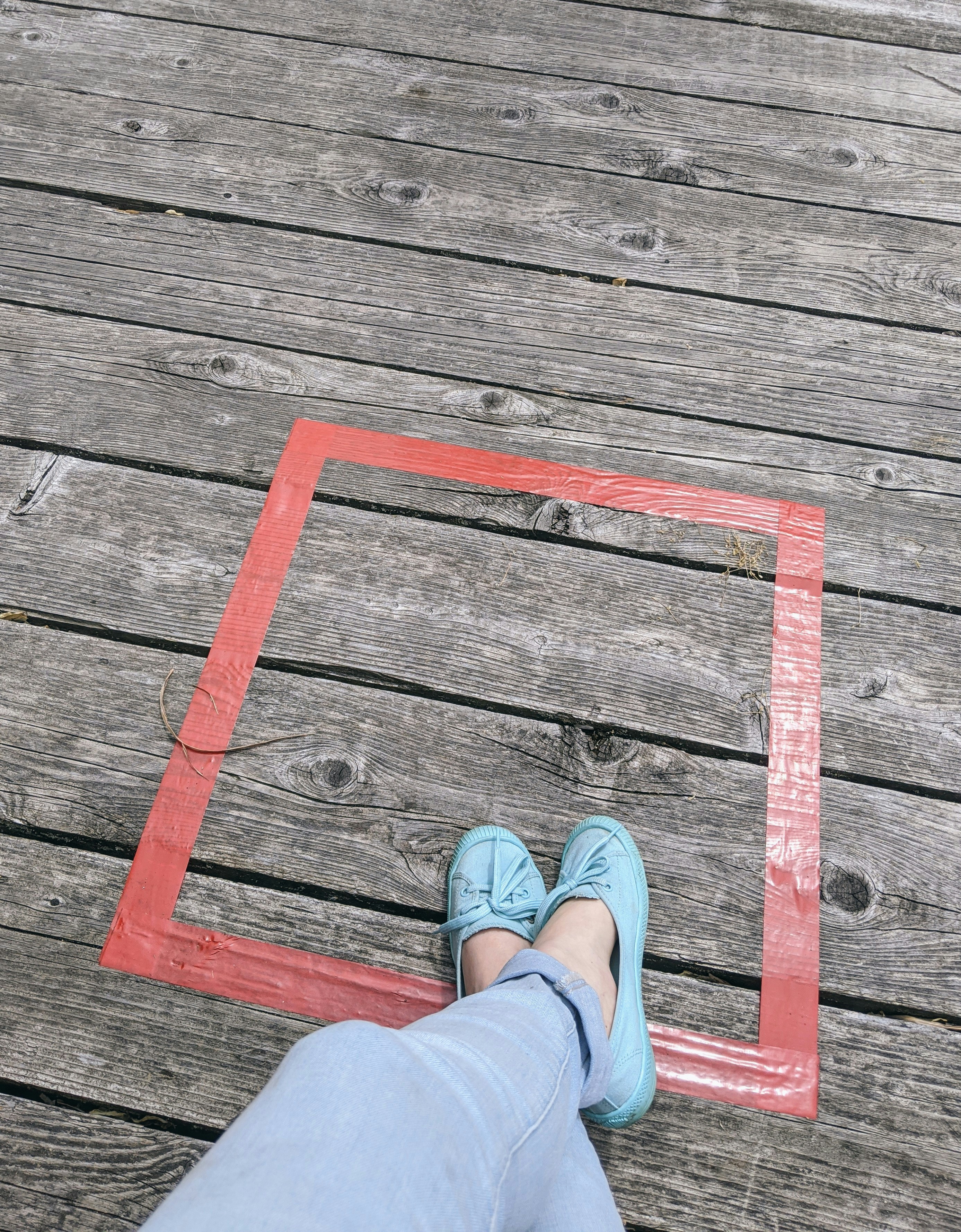 person in blue denim jeans and brown leather shoes standing on brown wooden plank