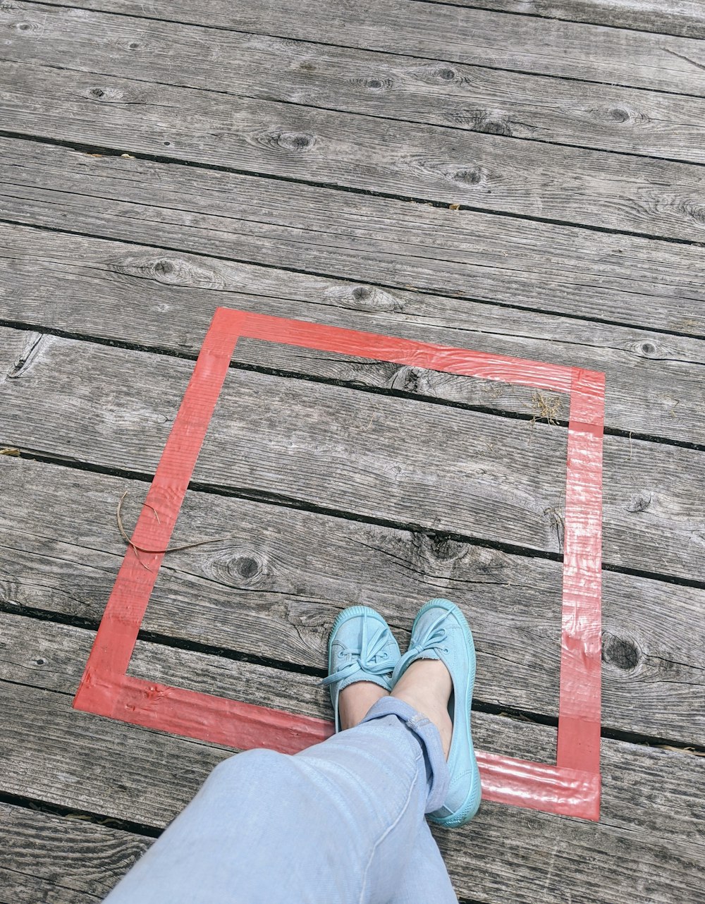 person in blue denim jeans and brown leather shoes standing on brown wooden plank