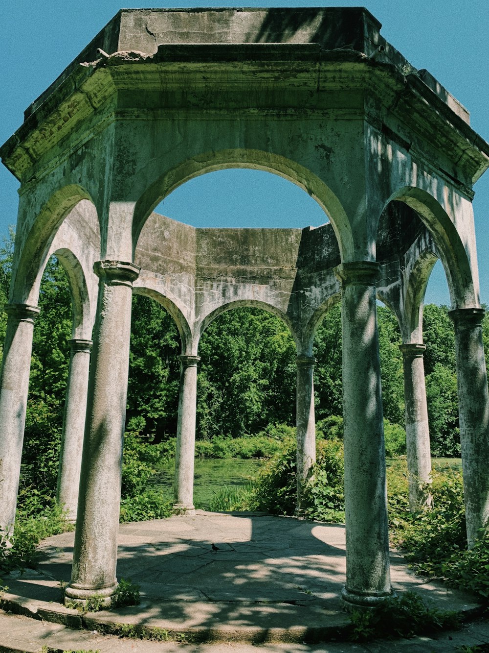 gray concrete arch near green trees during daytime