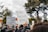 A diverse group of people participating in a protest with signs advocating against racism, surrounded by trees under a cloudy sky. Prominent signs include messages like Black Lives Matter and End Racism Now.