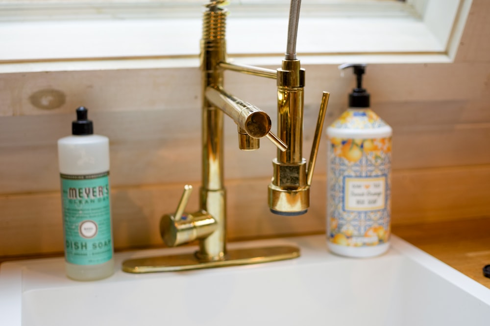 stainless steel faucet beside white and blue plastic bottle