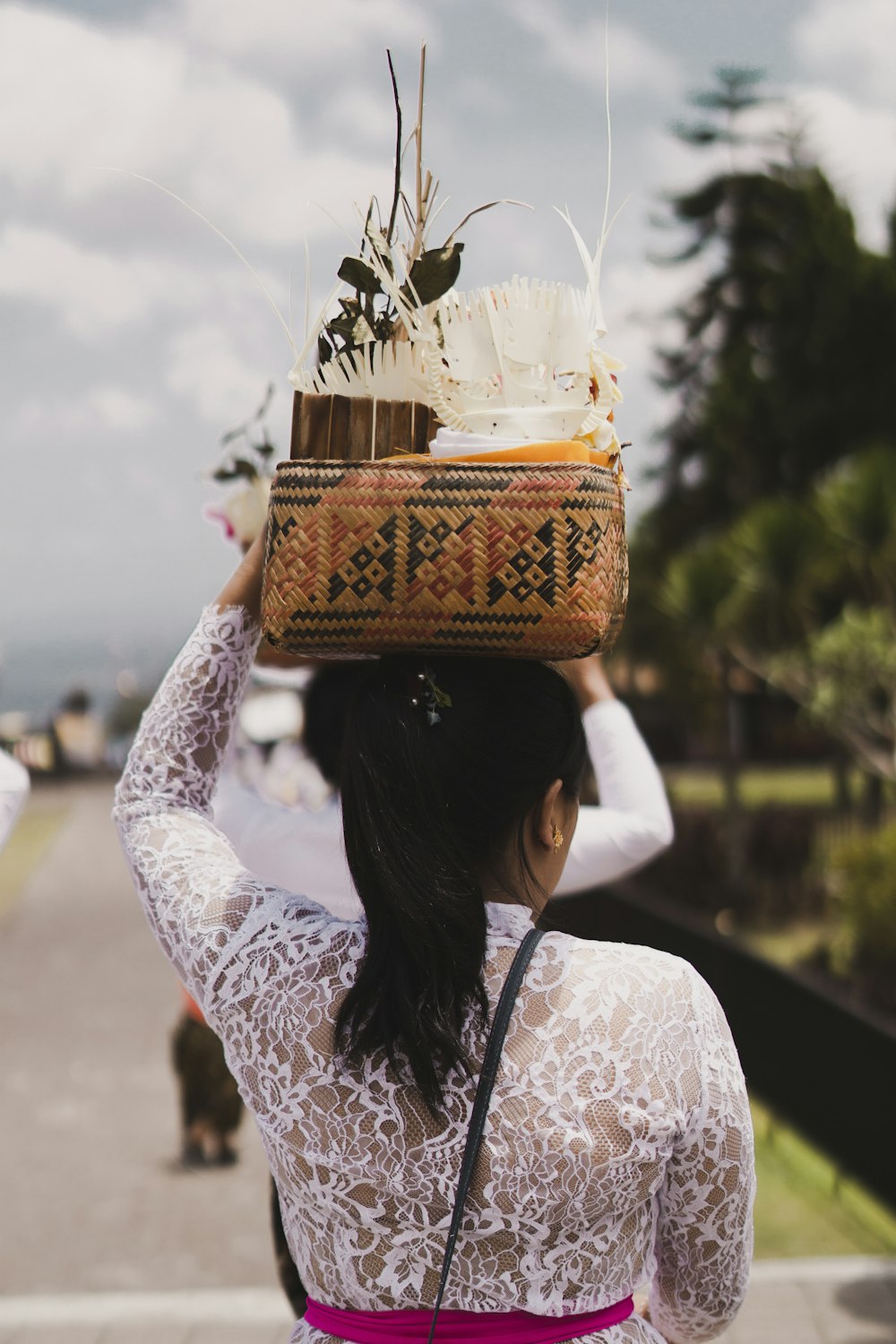 woman in white and red floral long sleeve shirt holding clear glass jar with white flowers