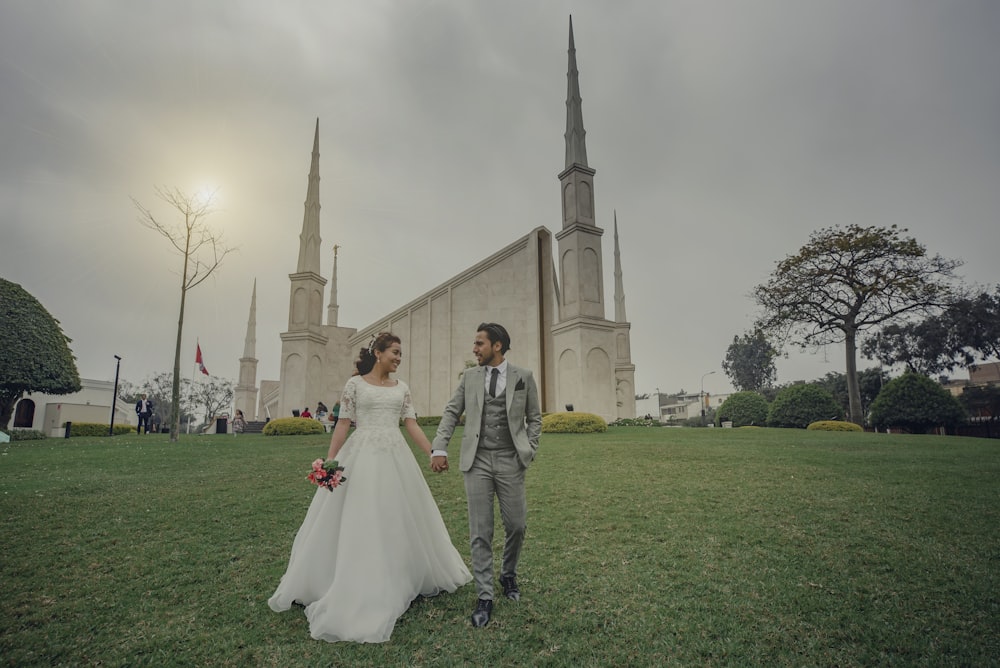a bride and groom walking in front of a church