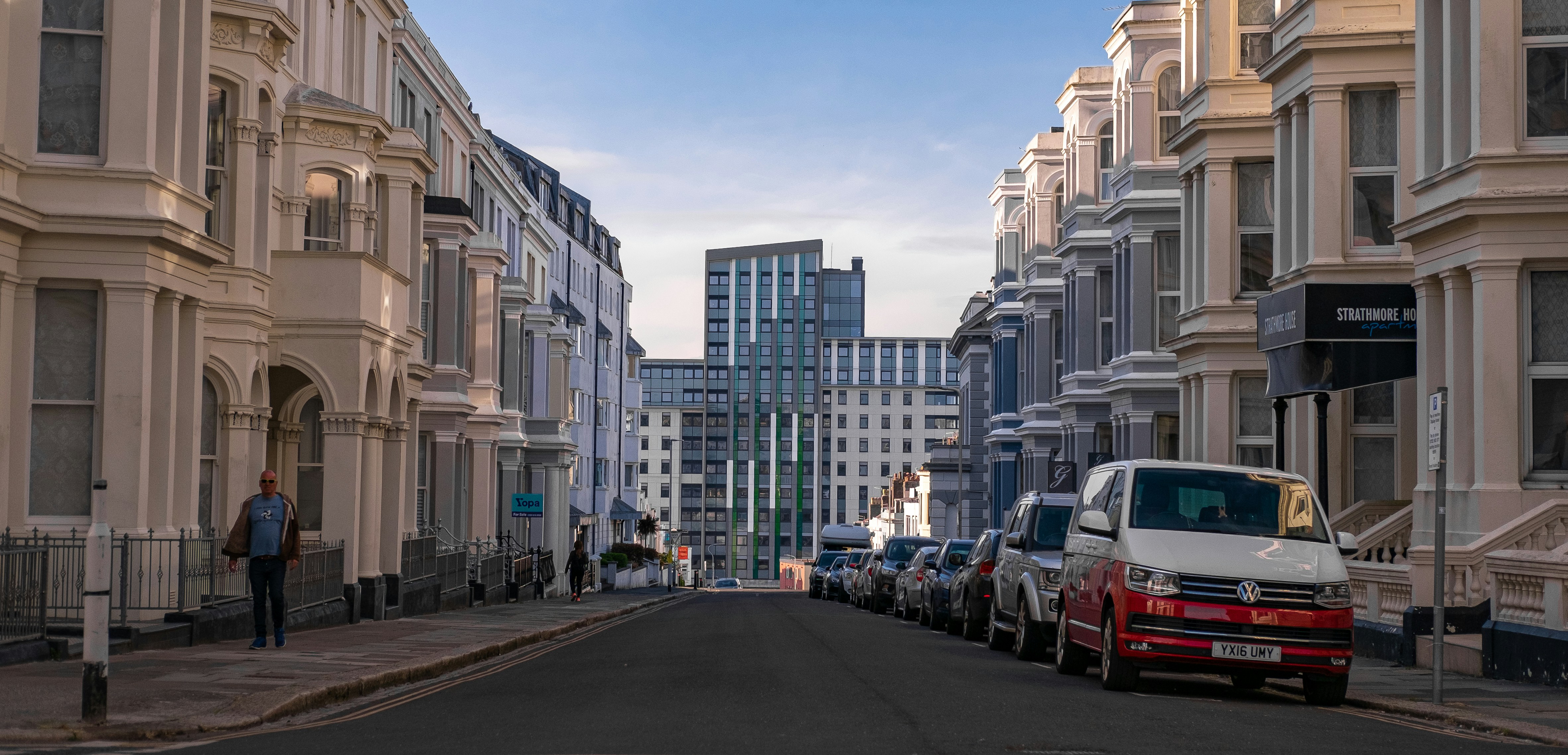 cars parked on the side of the road near high rise buildings during daytime