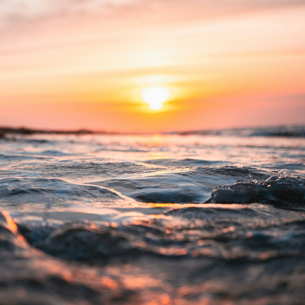 ocean waves crashing on shore during sunset