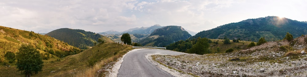 gray asphalt road near green mountains during daytime