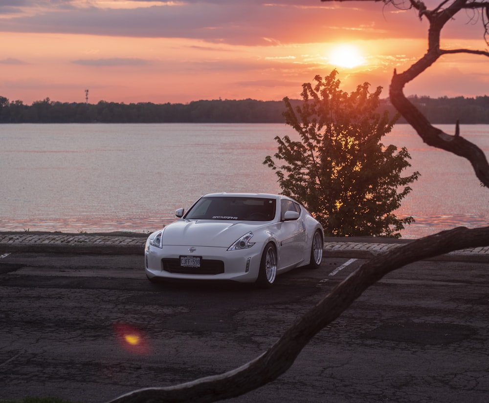 white porsche 911 parked near body of water during sunset