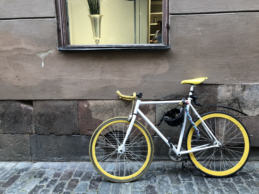 black and white road bike leaning on brown brick wall