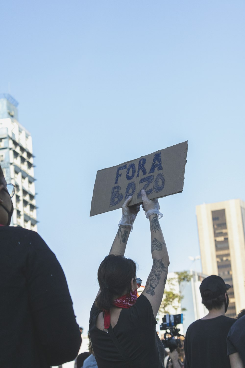 Hombre con camisa negra sosteniendo letreros azules y blancos durante el día