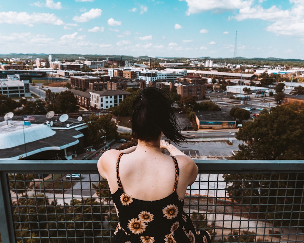 woman in black and white floral spaghetti strap top standing near black metal fence during daytime