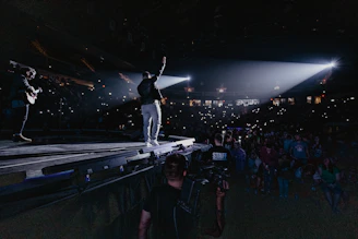 man in black jacket and blue denim jeans standing on ice hockey field