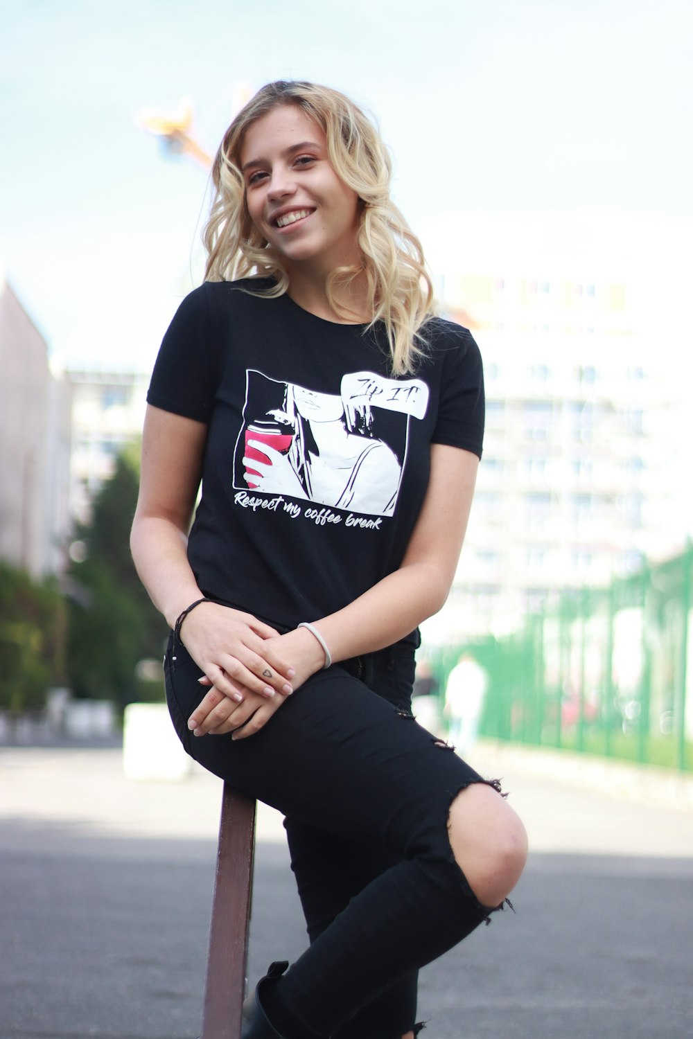 woman in black and white crew neck t-shirt and black pants sitting on brown wooden