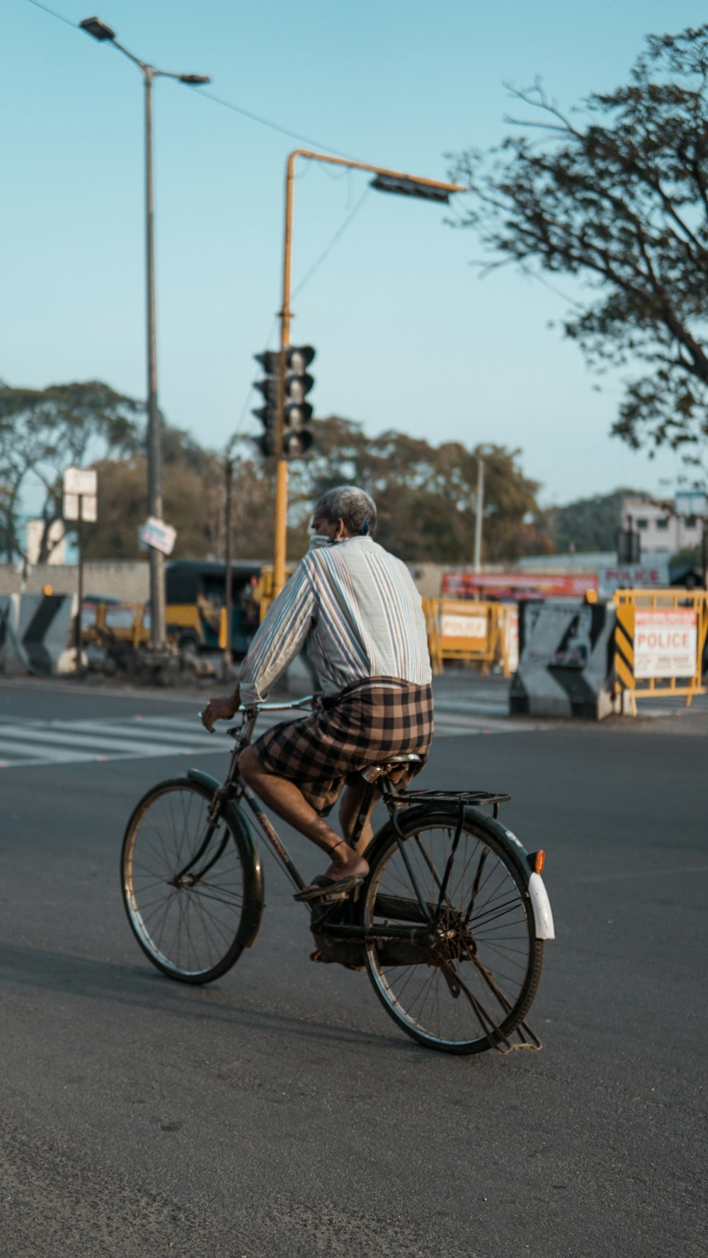 낮 동안 검은 도시 자전거를 타고 흰색과 갈색 격자 무늬 드레스 셔츠를 입은 남자