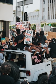 A group of passionate activists using bullhorns and digital signs outside a shady car dealership, rallying for consumer rights.