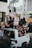 A group of people are gathered in a protest, with some individuals sitting on the roof of a white vehicle. They are holding up various signs in support of racial justice and police reform. The scene is dynamic and captures the energy of a large crowd engaged in activism.