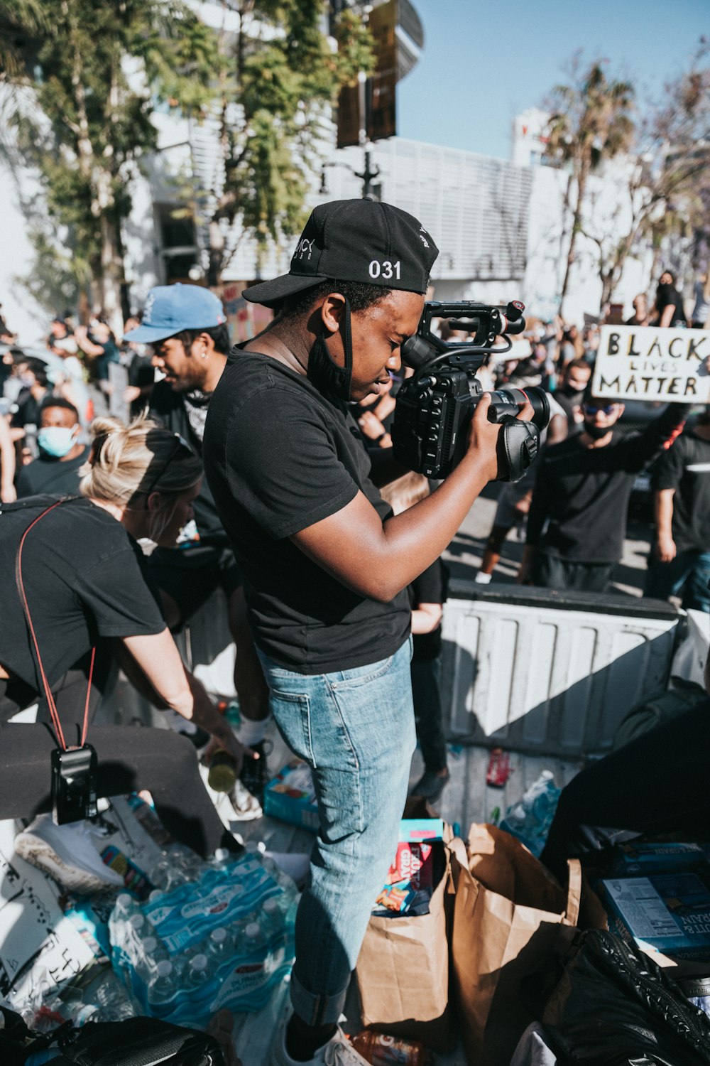 man in black t-shirt and blue denim jeans holding black dslr camera